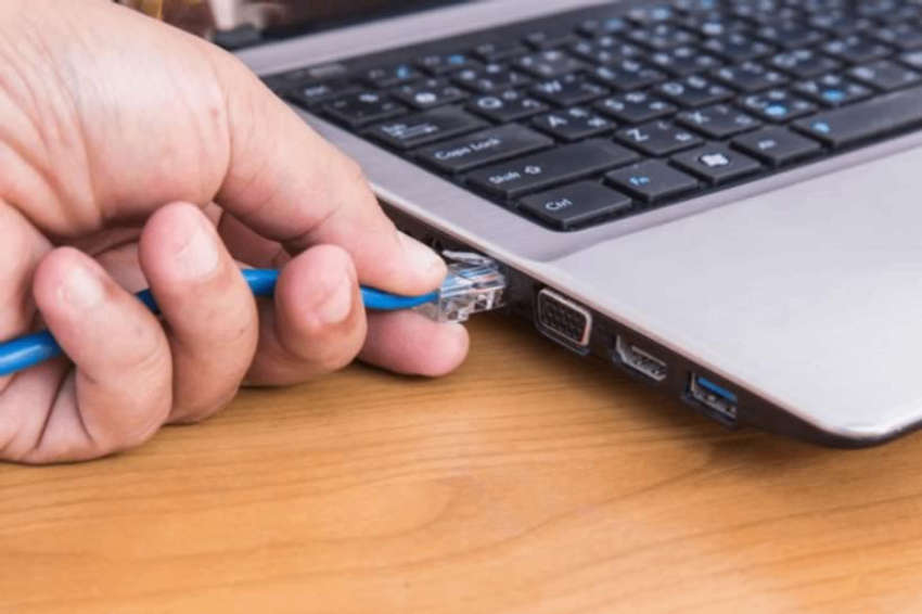 someone plugging an Ethernet cable into a laptop RJ45 port