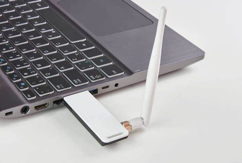 a USB wireless adapter with a visible antenna plugged into a laptop